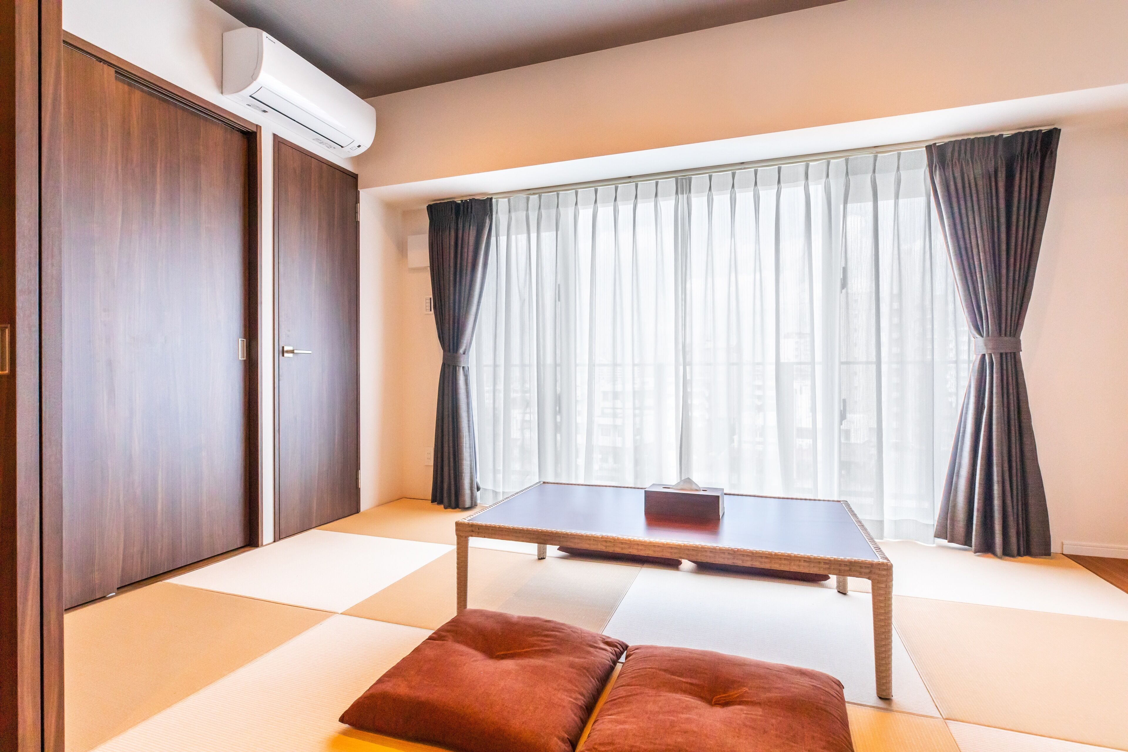 A room with tatami flooring, a low table, and a futon bed.