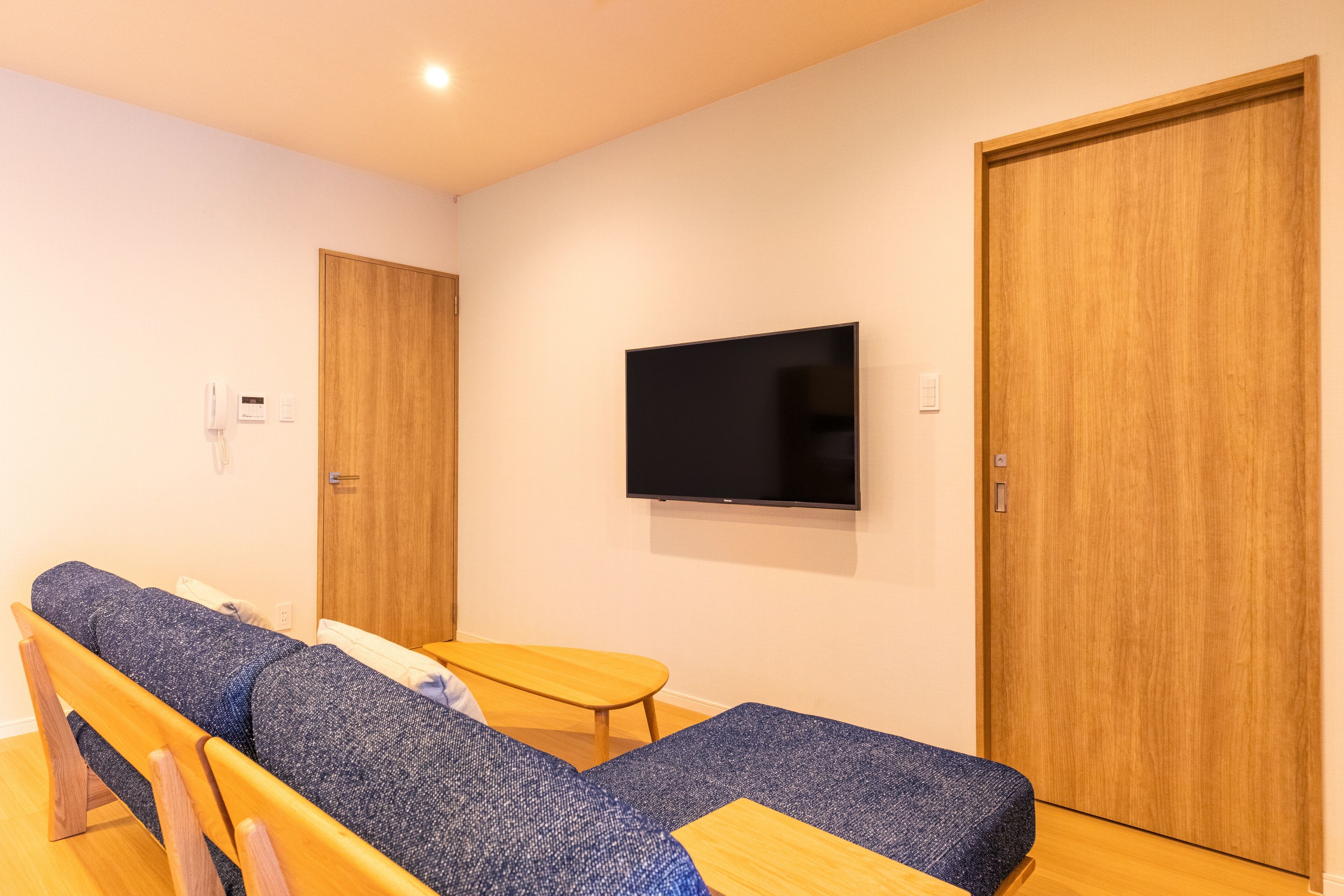 A room with a sofa, a small table, and a TV mounted on the wall.