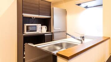 A compact kitchen with a built-in microwave, a coffee maker, and a stainless steel refrigerator.