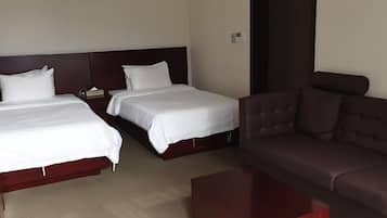 Habitación de hotel con dos camas, un sofá y una mesita.