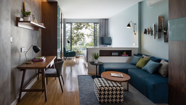 Un salon moderne avec un bureau en bois, un canapé bleu et une table basse ronde.