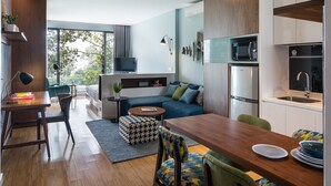 Un salon moderne avec une table à manger en bois, des chaises et un canapé. Il y a également un coin cuisine équipé d’un four à micro-ondes, d’un réfrigérateur et d’un évier.