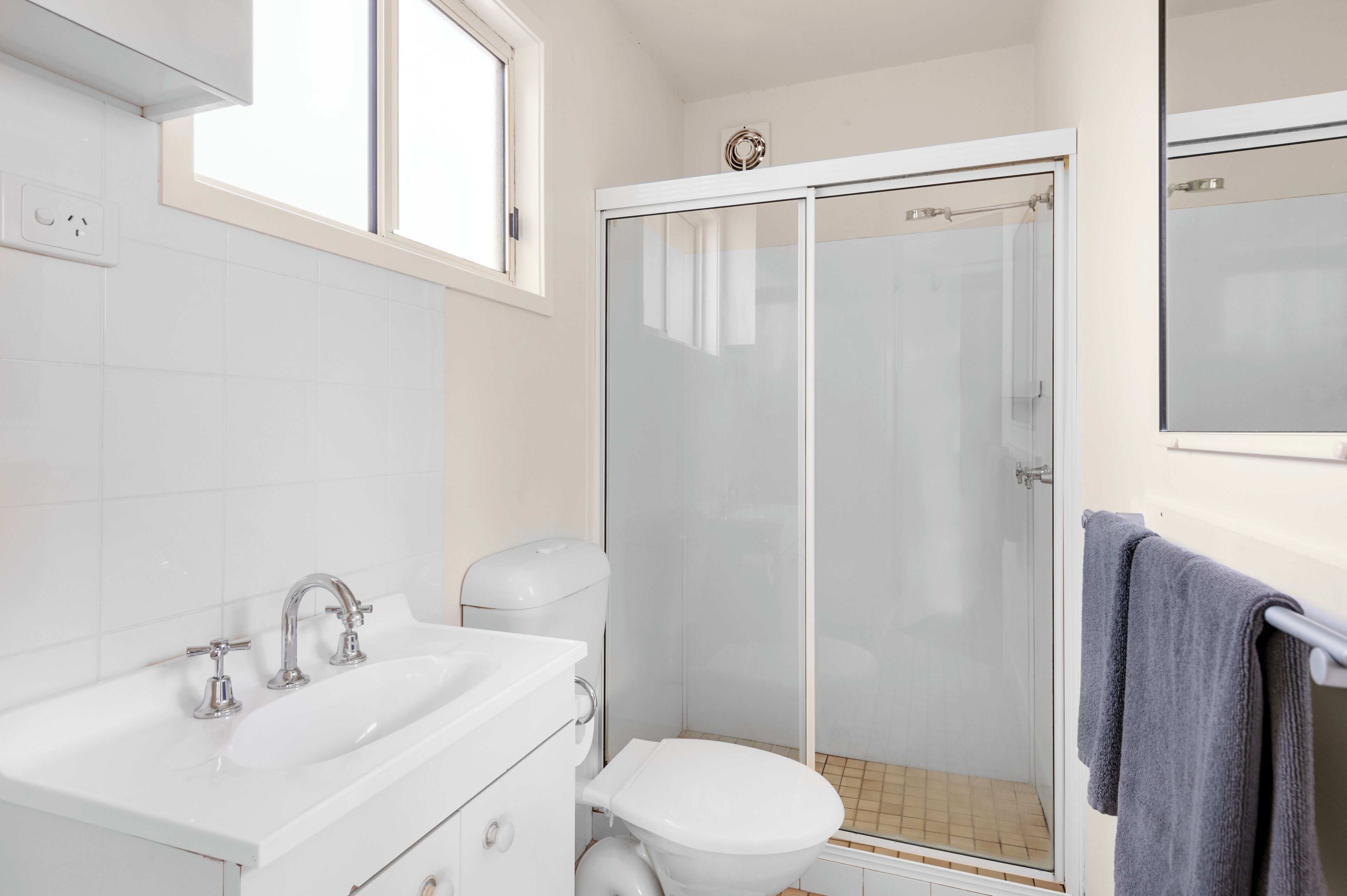 A bathroom with a white sink, toilet, and glass-enclosed shower.
