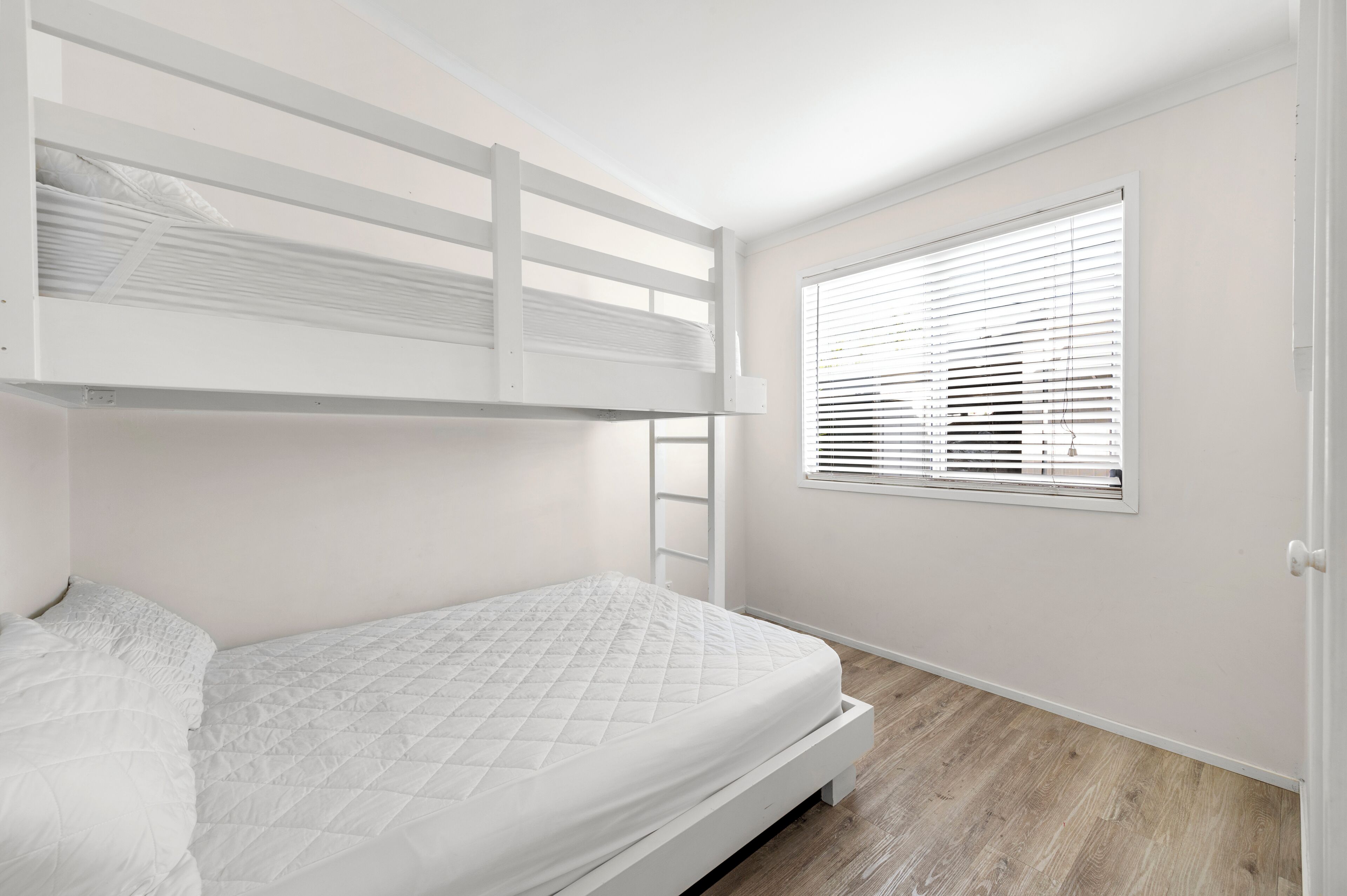 Ein Schlafzimmer mit Etagenbetten, einem Fenster und einer Klapptreppe.