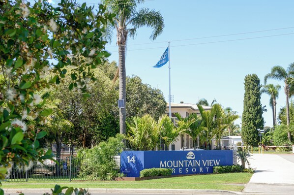 A sign for Mountain View Resort with a clear view of the surrounding greenery and a flagpole. - Mountain View Resort (Shoalhaven Heads)