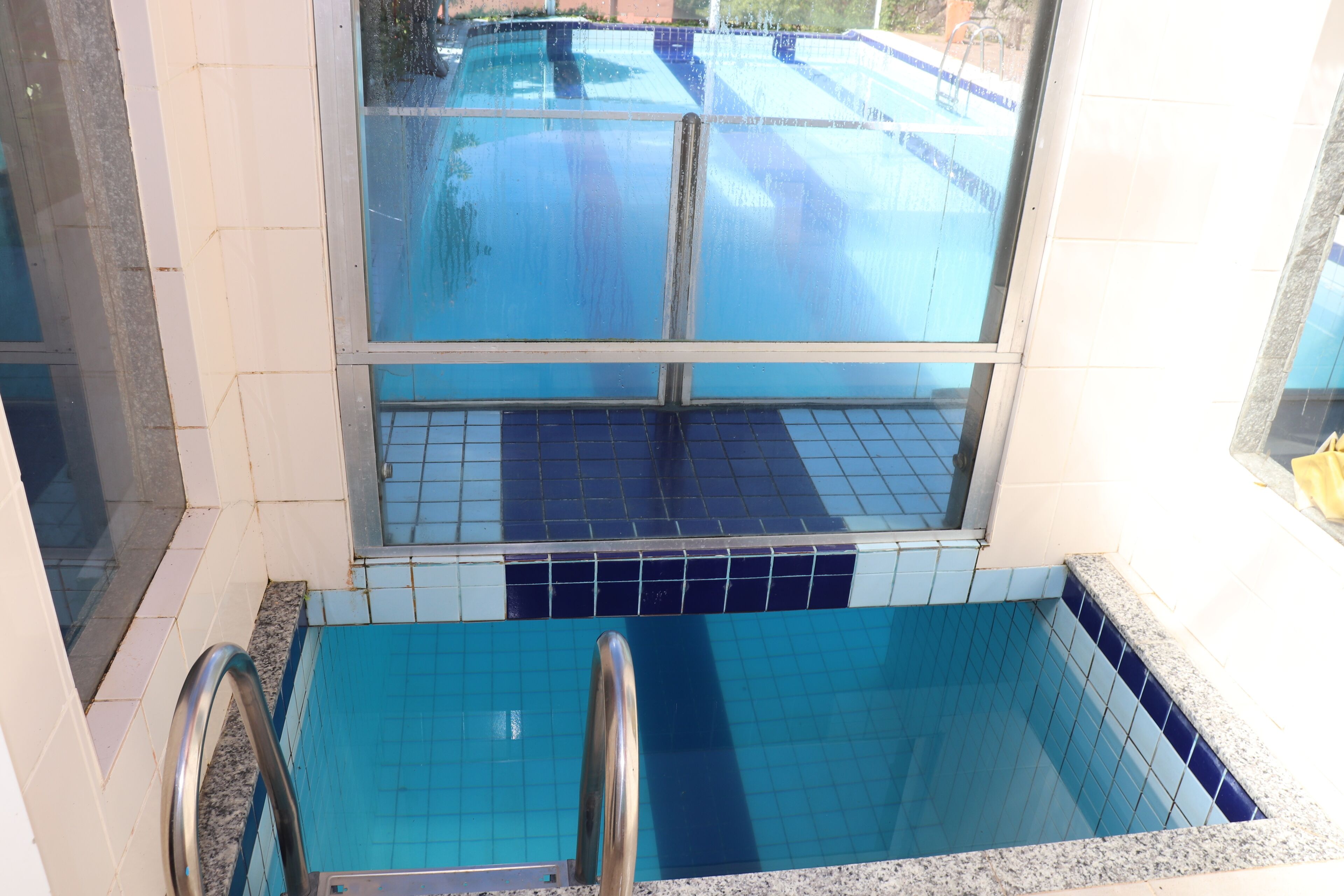 A swimming pool with a glass enclosure and a metal ladder.