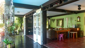 A spacious room with a wooden floor, a dining area with a table and chairs, and a green wall with a heart-shaped decoration.