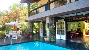 A swimming pool with a patio area, outdoor seating, and potted plants.