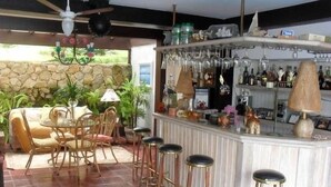 A bar area with stools, a counter, and a stone wall in the background.