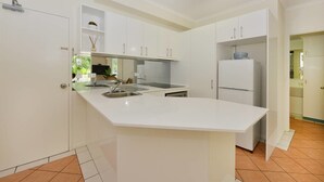 A modern kitchen with white cabinetry, a central island with a sink, and a built-in oven.