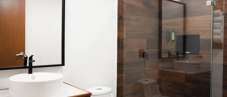 A modern bathroom with a white sink, a toilet, and a glass-enclosed shower area.