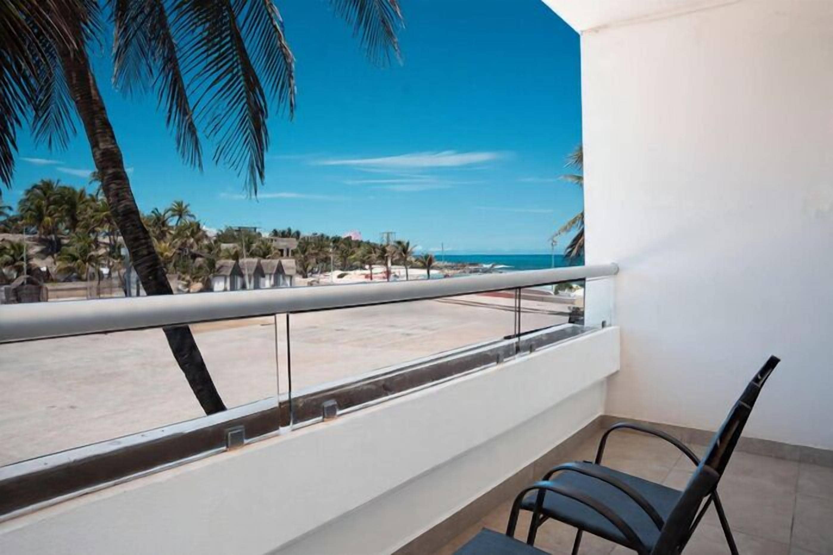 A balcony with a clear view of the beach and palm trees.