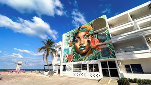 Un edificio con un mural, una palmera y un cielo despejado.