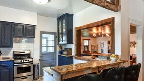 A modern kitchen with dark cabinets, a stainless steel oven, and a marble countertop.