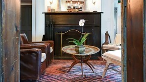 A cozy living room with a fireplace, leather sofas, a round coffee table, and a hanging light fixture.