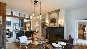 A spacious living room with a fireplace, a dining area with bar stools, and a kitchen visible through an open door.