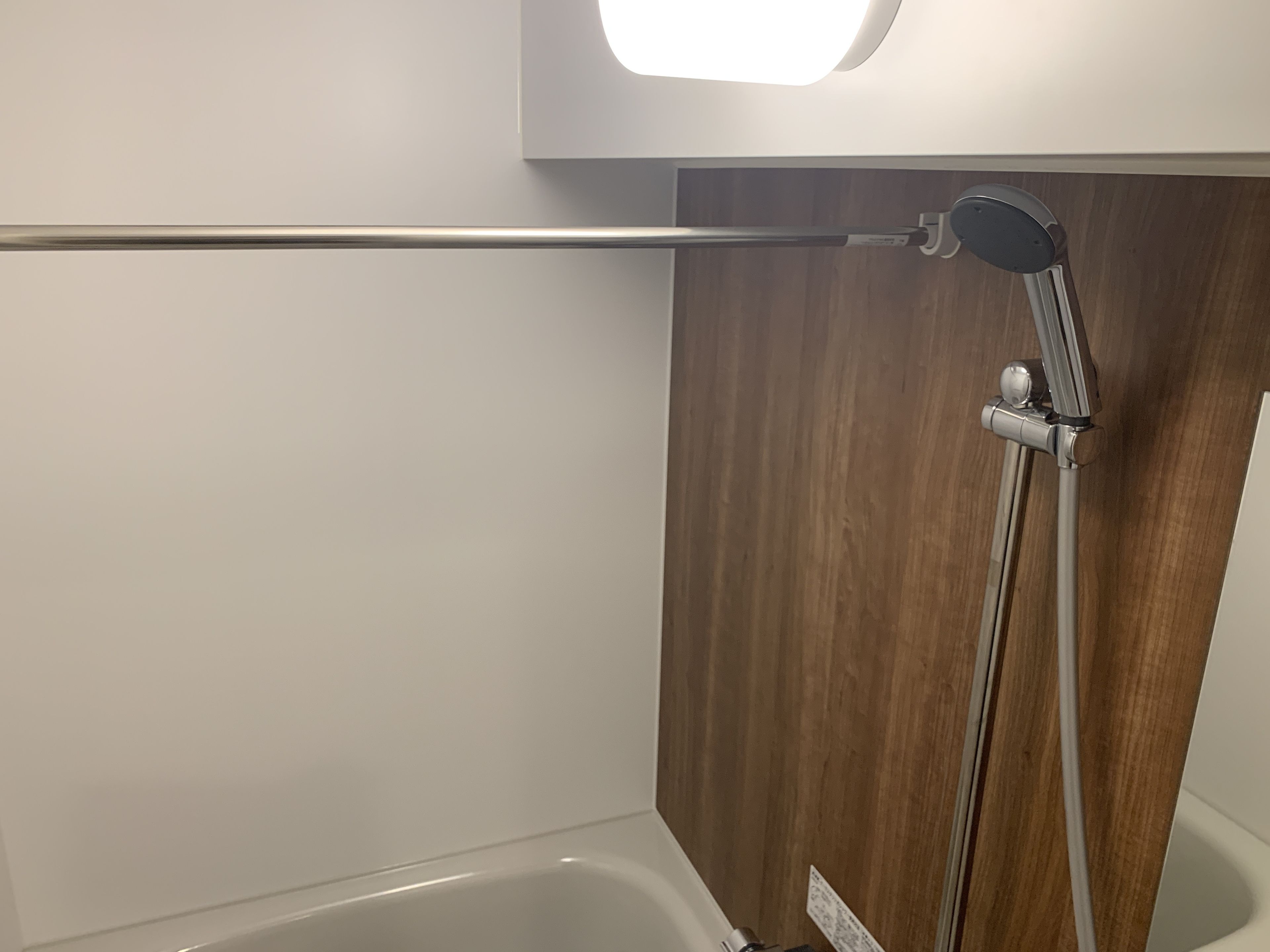 Een moderne badkamer met een wandpaneel van hout, een witte badkuip en een douchegedeelte met een chromen kraan.