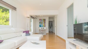 Una sala de estar moderna con un sofá blanco, una mesa de centro y un televisor de pantalla plana.