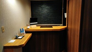 A hotel reception desk with a computer monitor, a telephone, and a small counter with a few items on it. - Hotel Takanoya (Hadano)