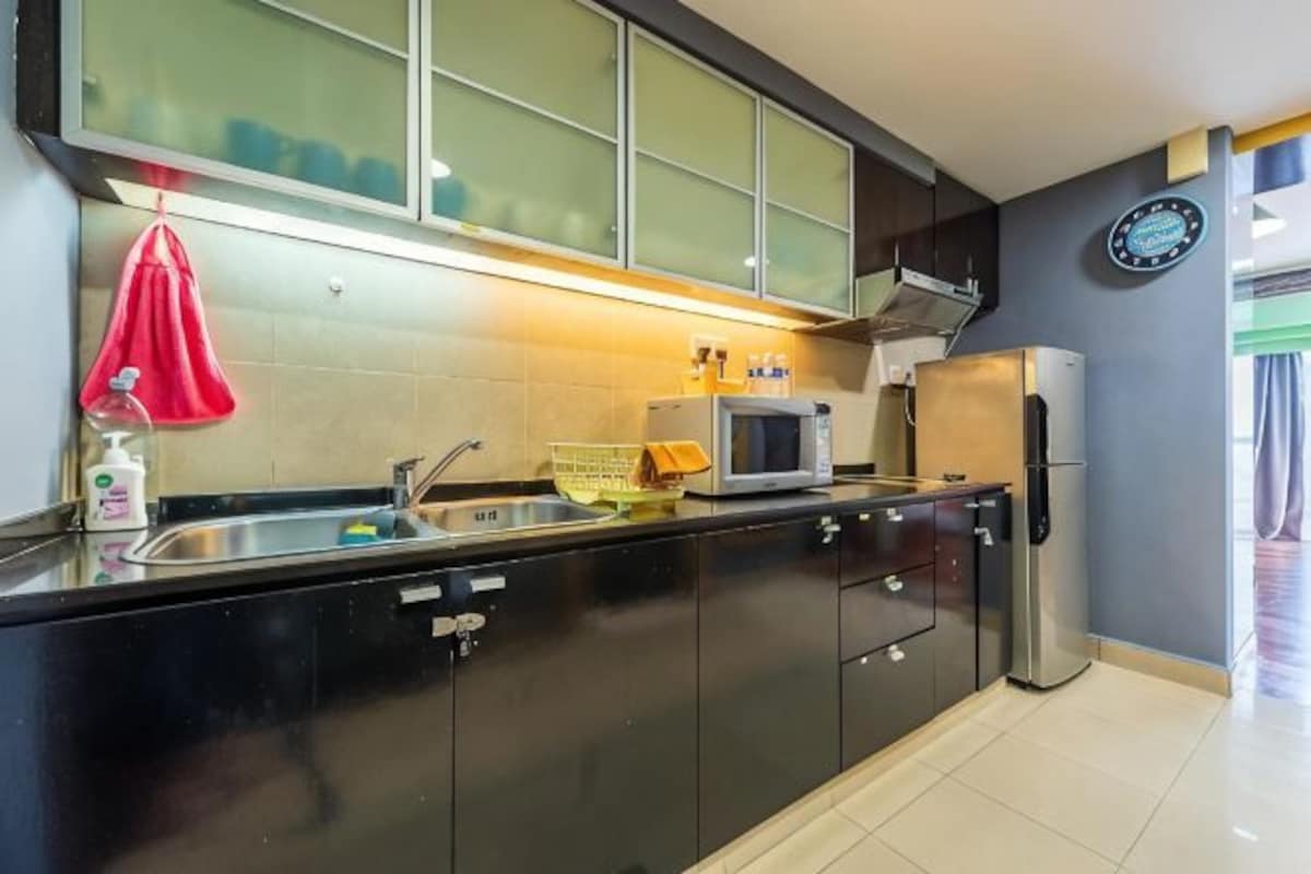 Una cocina con gabinetes negros, un microondas, un refrigerador, un fregadero y una toalla roja colgada en la pared.
