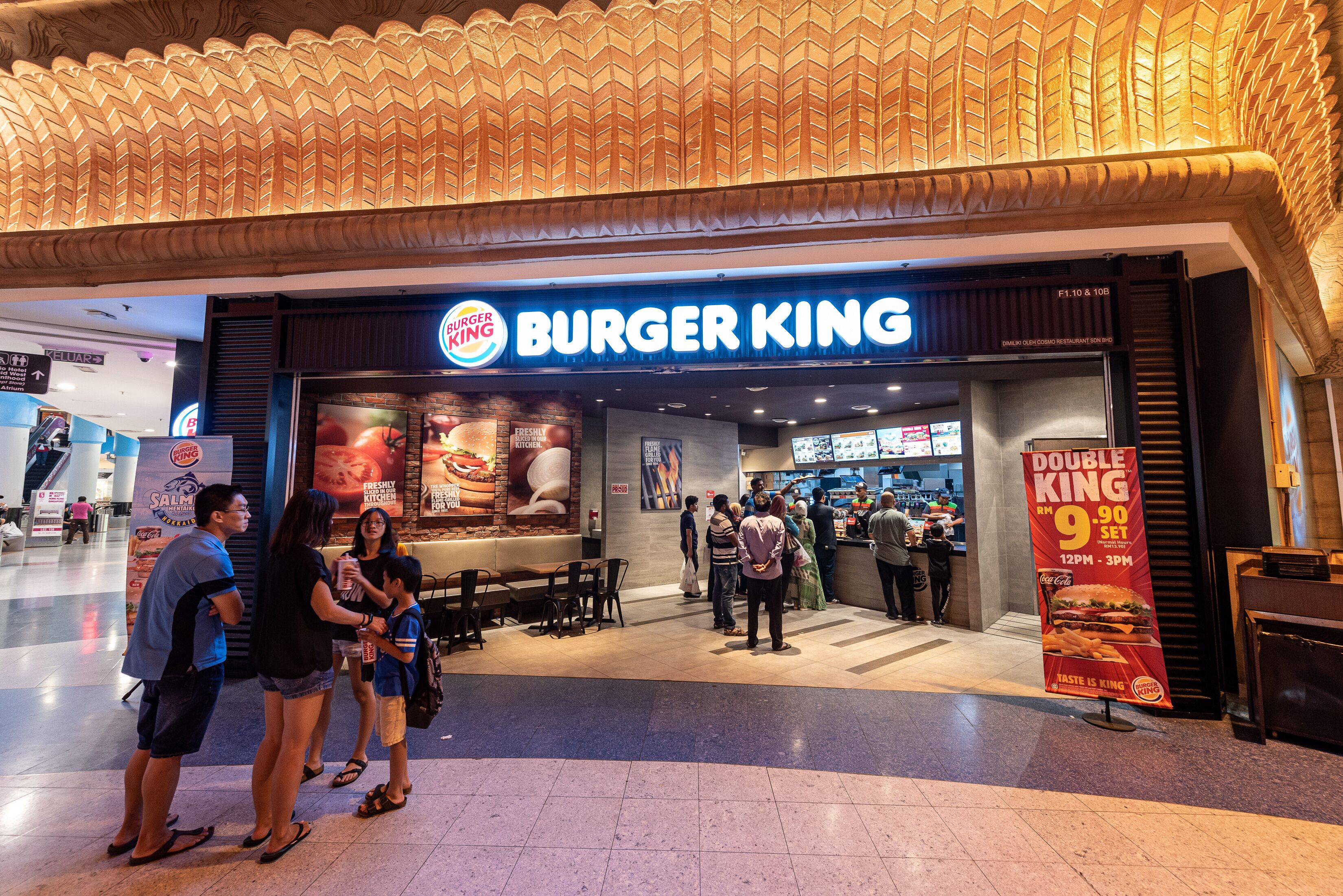A Burger King restaurant with a modern design, including a prominent sign and a promotional poster.