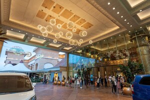 Un'ampia hall con soffitto alto, decorazioni elaborate e lampade moderne.