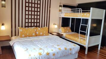 Un dormitorio con literas, una cama grande con ropa de cama estampada de estrellas, suelo de madera y dos lámparas fijadas a la pared.