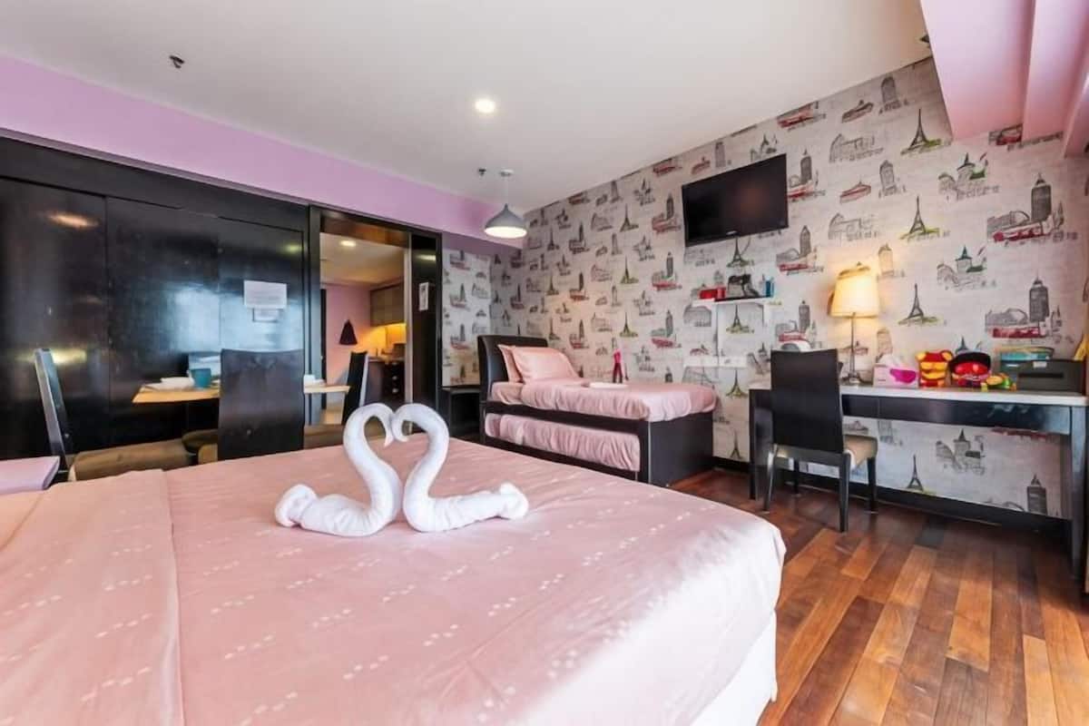 A hotel room with a bed, a desk, a chair, and a TV.