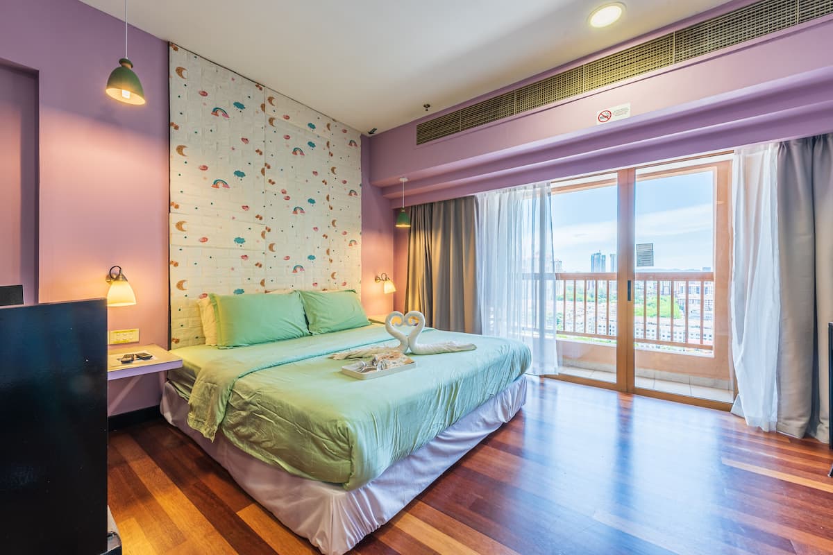 A hotel room with a bed, a TV, a wall with a climbing wall design, and a balcony with a view.