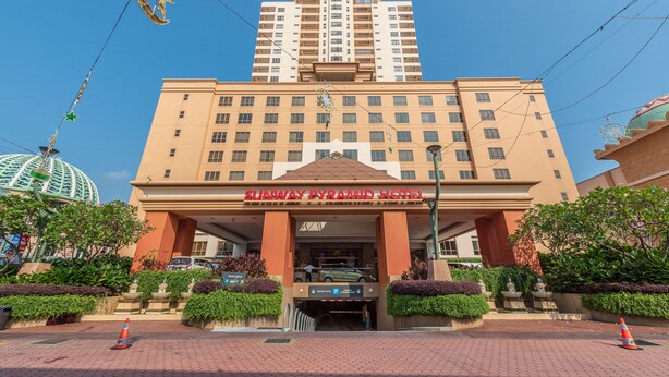 A hotel with a large entrance, a parking area, and a clear sky.