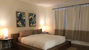 A modern bedroom with a wooden platform bed, two wall-mounted lamps, and a large window with curtains.