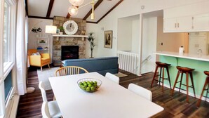 Ein modernes Interieur mit einem Esstisch, Stühlen, einem blauen Sofa, einer Küchenzeile und einem Kamin.