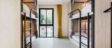 Una habitación con literas, una ventana con cortinas y vistas a la vegetación.