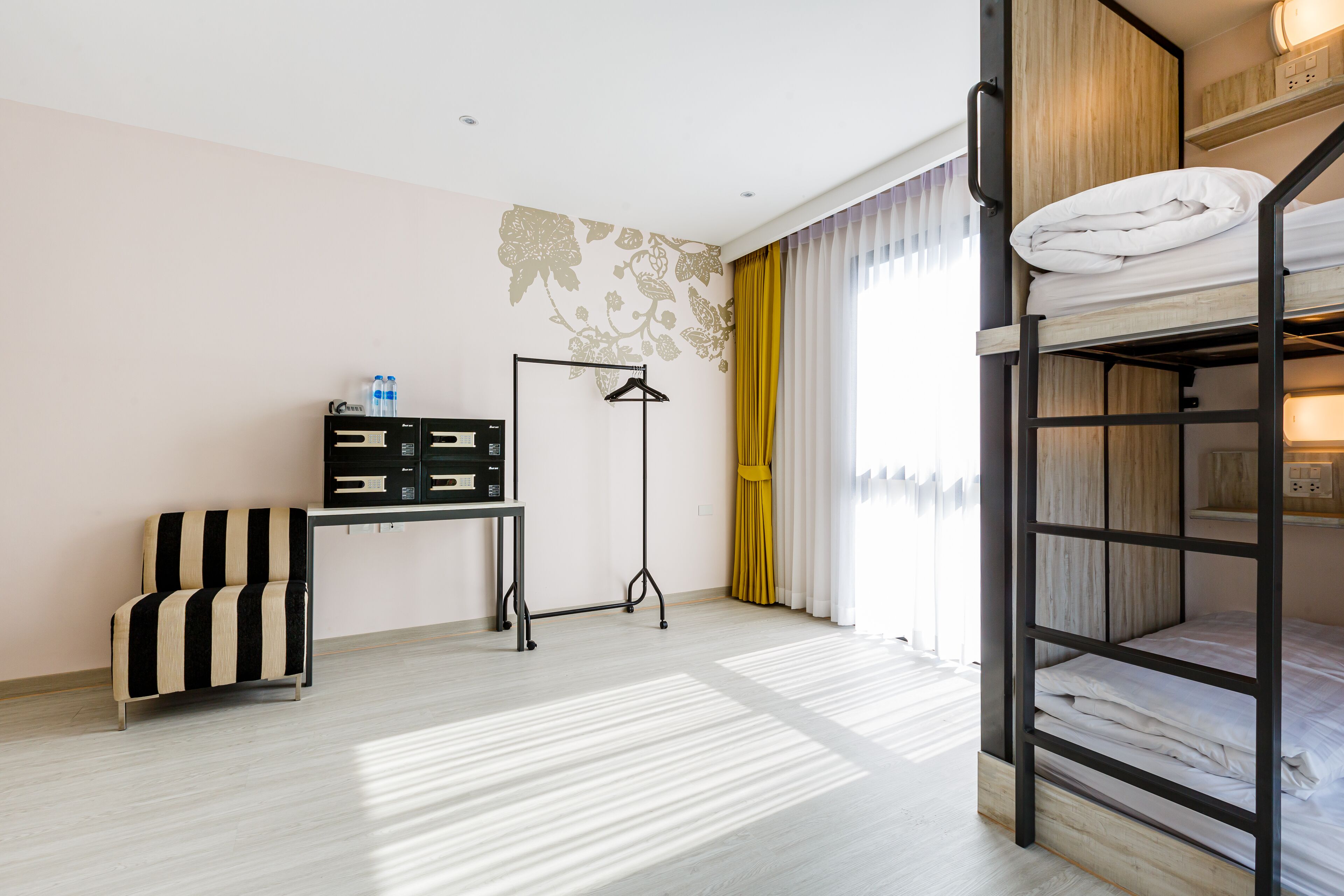 Una habitación con literas, un escritorio con silla, una lámpara colgante y un armario.