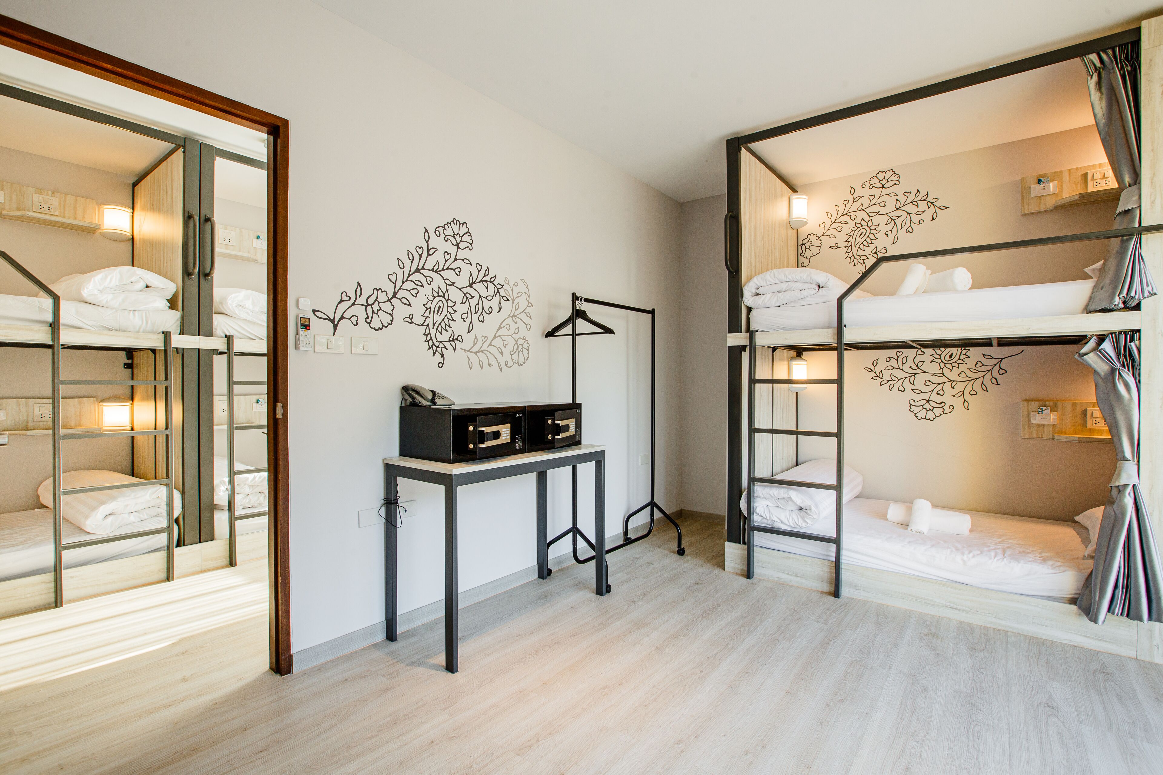 A compact hotel room with bunk beds, a desk, and a mirror.