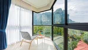 Un balcon donnant sur un paysage montagneux, une chaise et une petite table agrémentée d’une fleur.