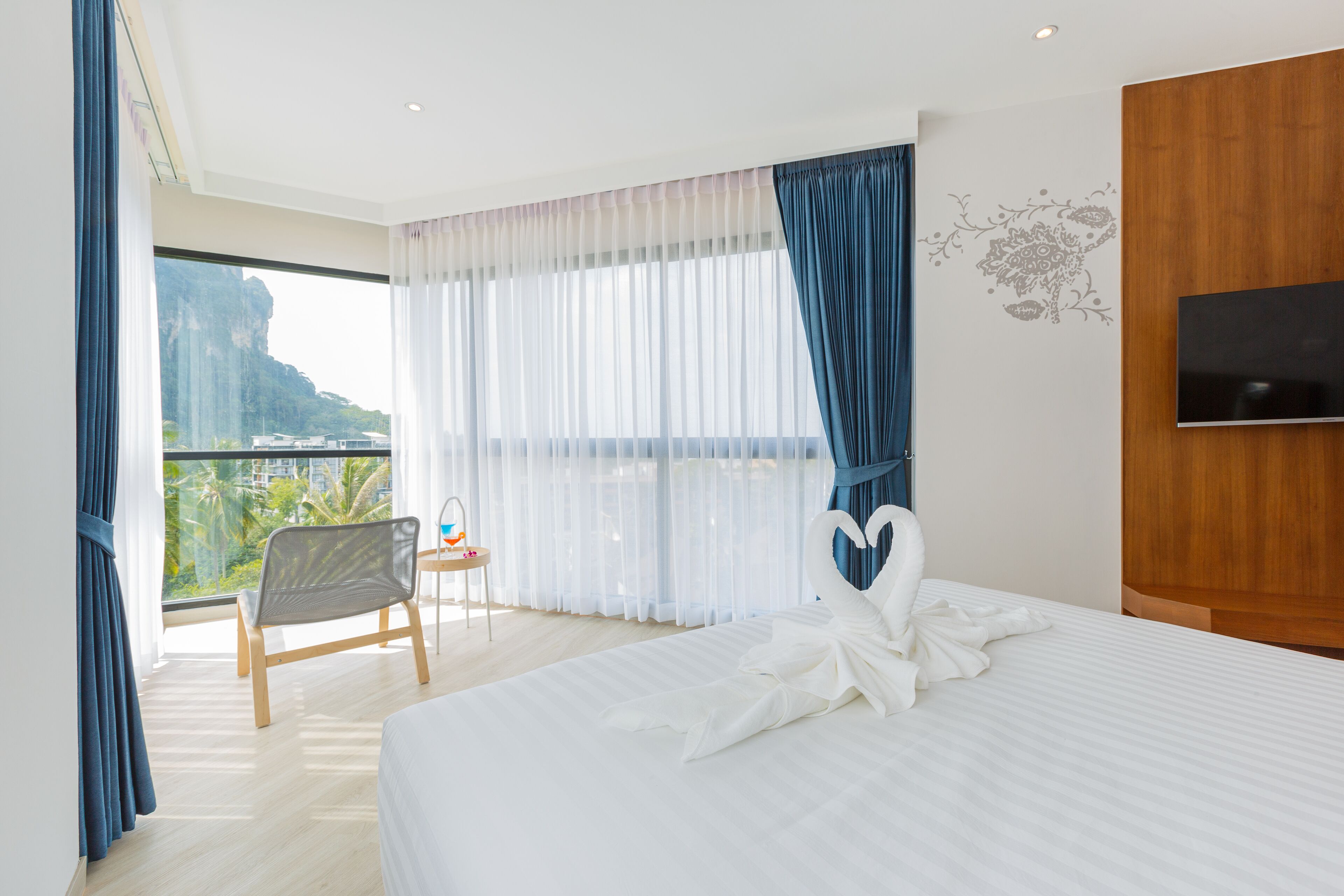 Habitación de hotel con una cama grande, televisión, sillón y vista a la montaña.