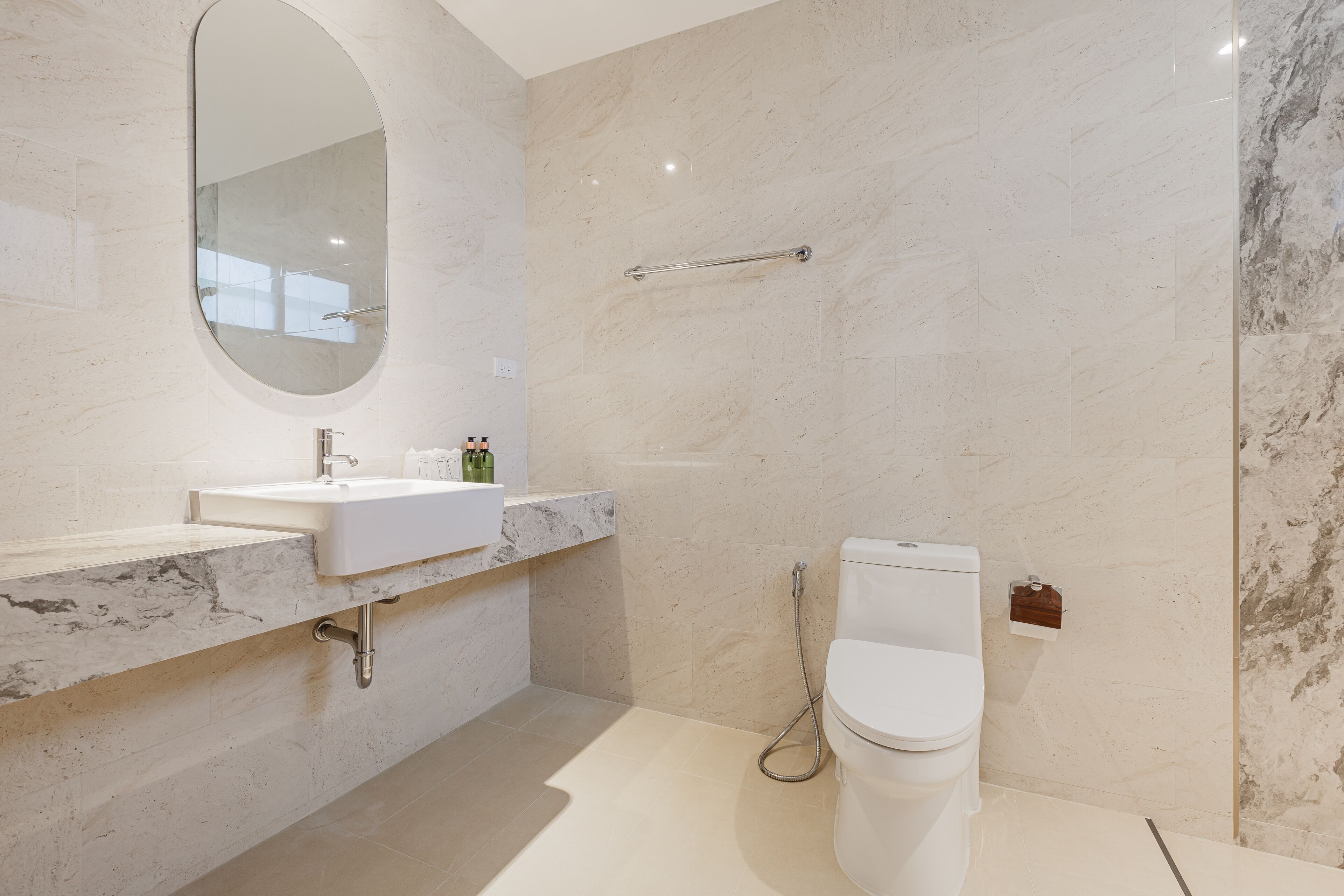 Une salle de bain moderne avec un lavabo en marbre, un grand miroir, des toilettes et un espace douche.