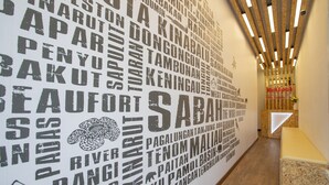 A hallway with a wall covered in large, bold text, likely representing various destinations or locations. - HotSpot at City Centre by SSVC (Kota Kinabalu)