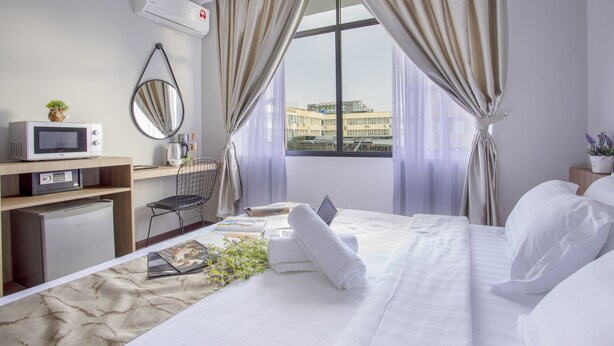 A hotel room with a bed, a desk with a computer, a microwave, and a small refrigerator. - HotSpot at City Centre by SSVC (Kota Kinabalu)