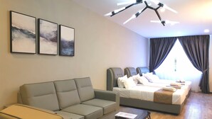 A modern hotel room with a sofa, a bed, a glass coffee table, and a ceiling light fixture. - HotSpot at City Centre by SSVC (Kota Kinabalu)