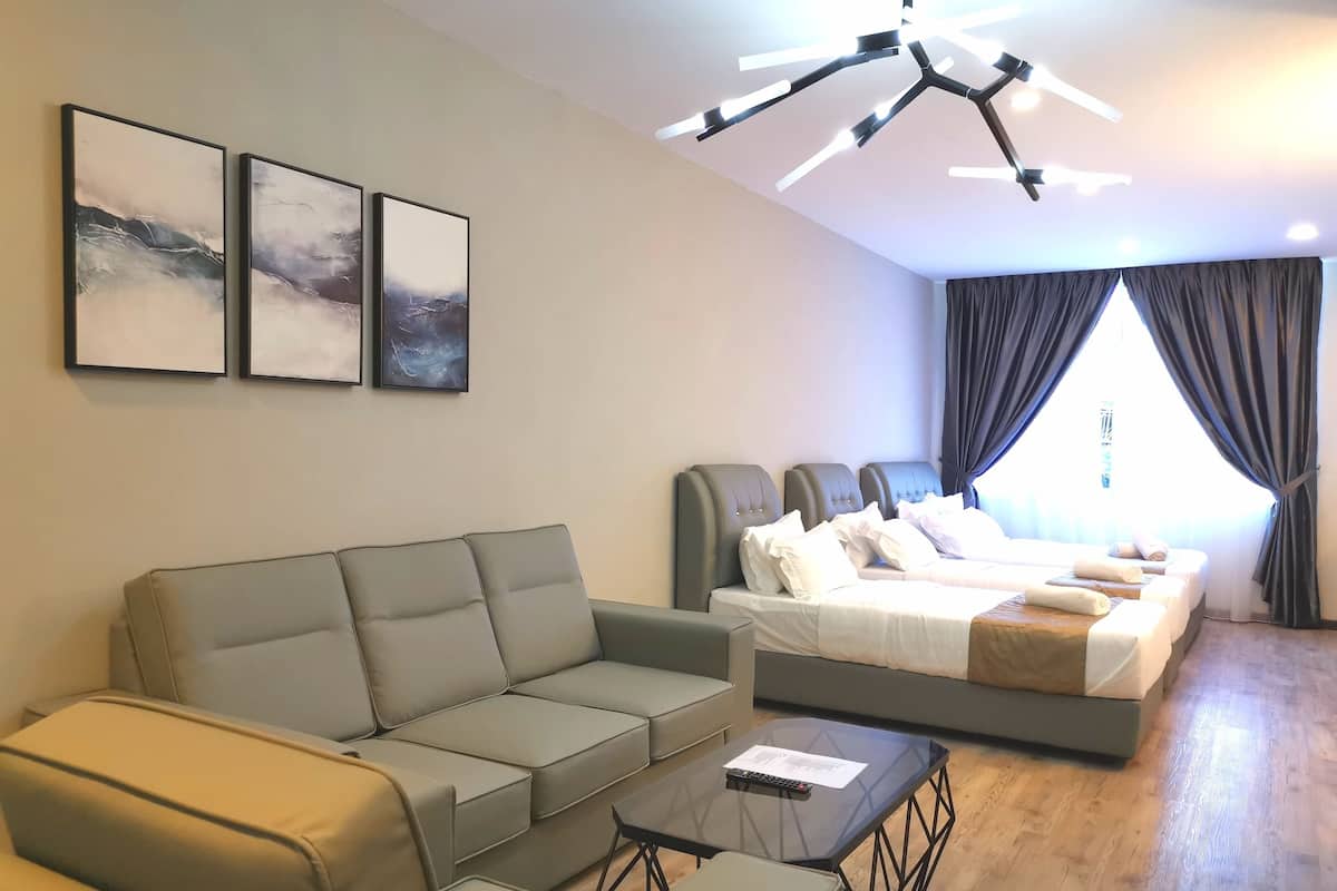 A modern hotel room with a sofa, a bed, a glass coffee table, and a ceiling light fixture.