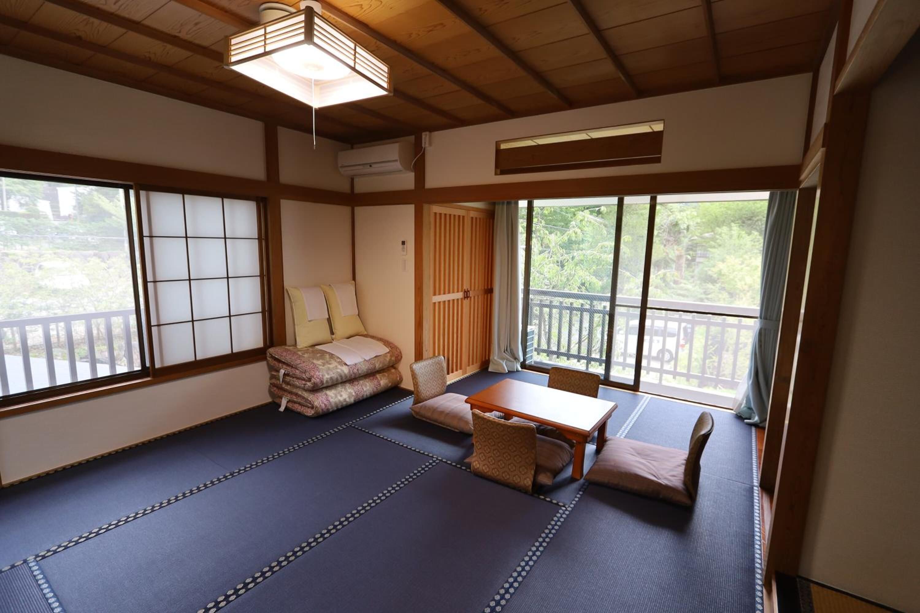Una habitación tradicional japonesa con suelo de tatami, una mesa baja y cojines.