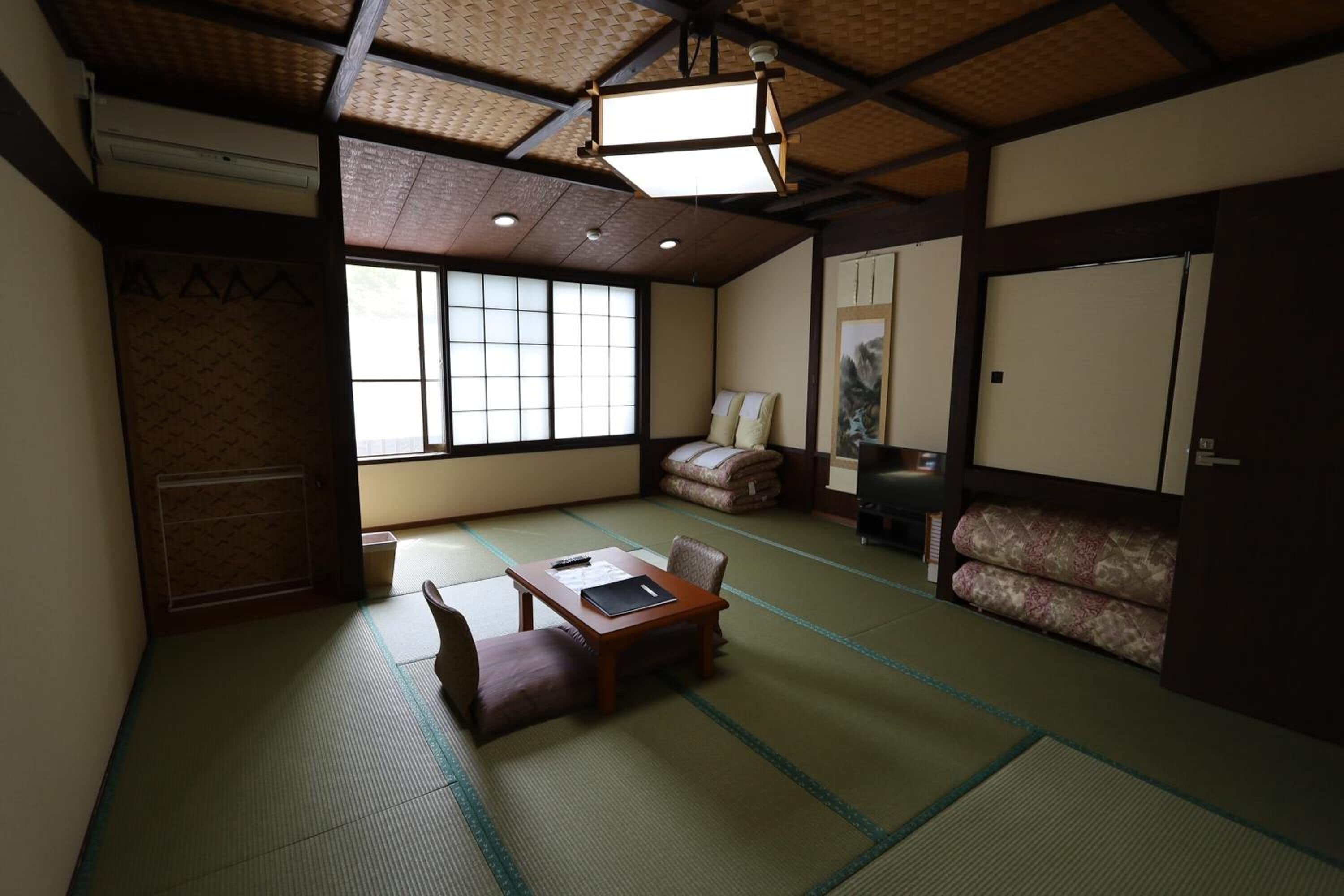 A traditional Japanese room with tatami flooring, a low table with cushions, a sofa, and a sliding door.