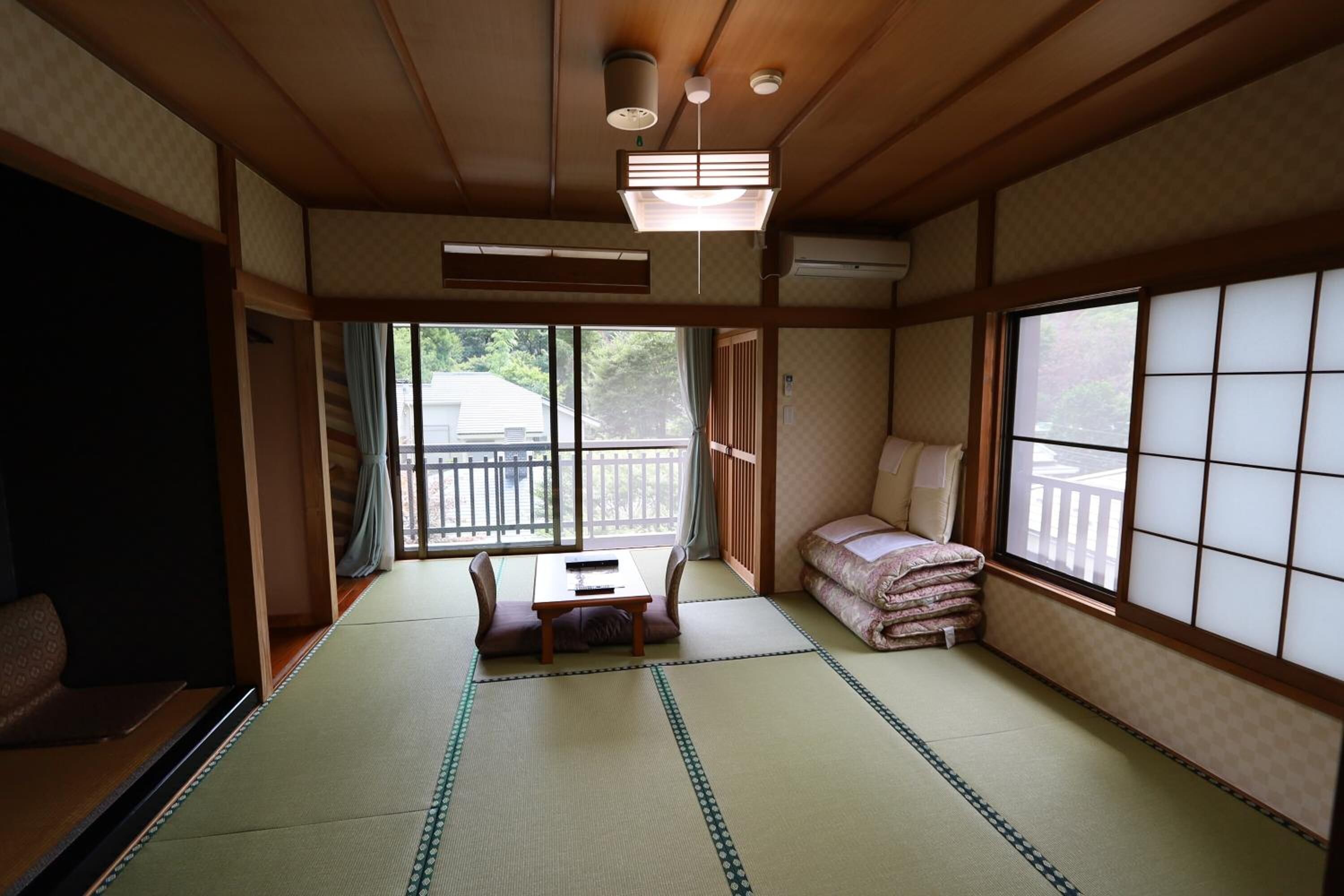 A traditional Japanese room with tatami flooring, a low table, cushions, and sliding doors.