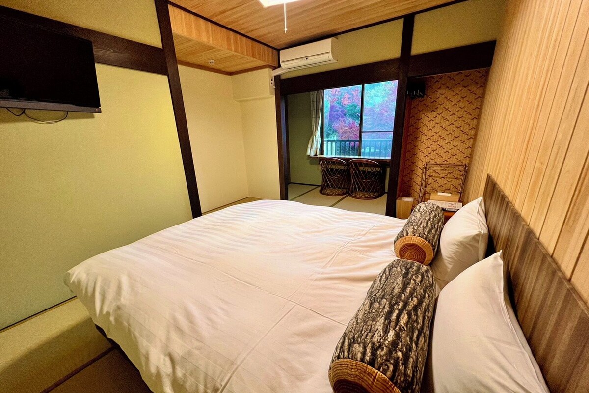 Ein Hotelzimmer mit einem großen Bett, einem Holzkopfende und einem an der Wand montierten Fernseher.