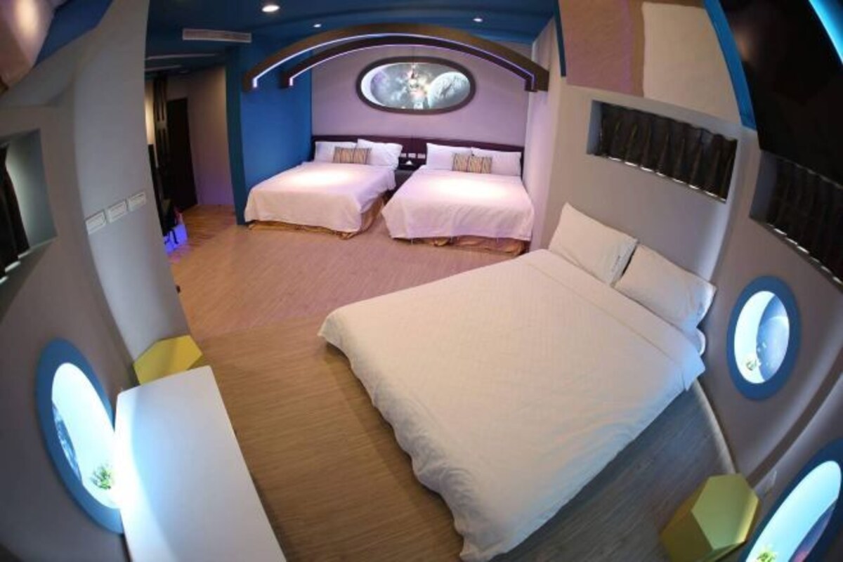 A modern hotel room with two beds, a circular skylight, and a wooden floor.