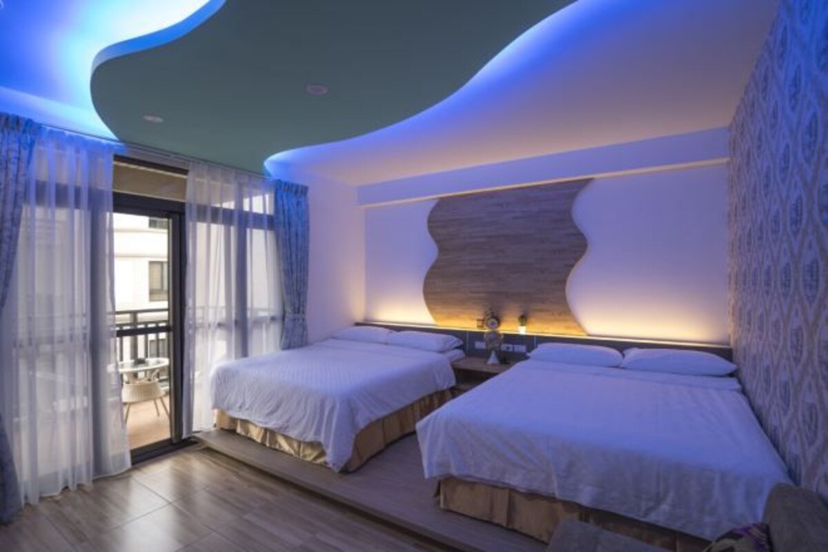 A modern hotel room with two beds, a balcony, and a unique ceiling design.