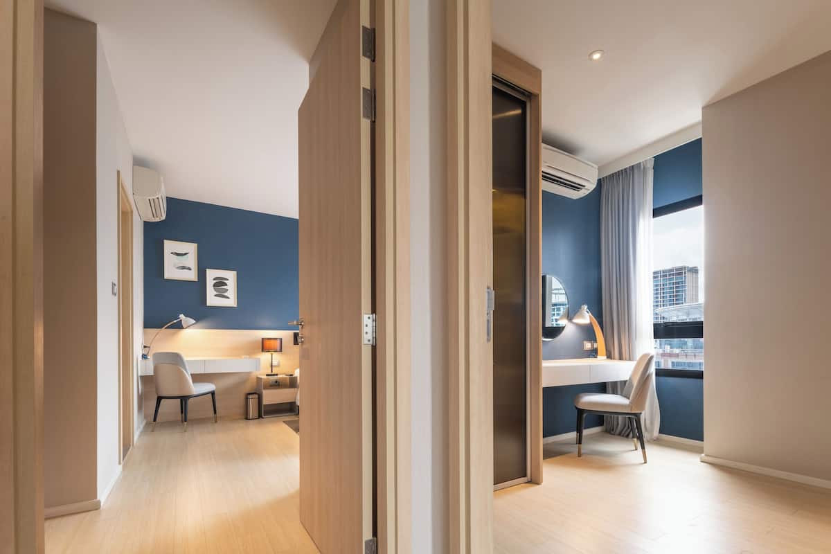 Habitación de hotel moderna con escritorio, silla y vistas a la ciudad a través de un amplio ventanal.