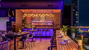 Un bar interior con diseño moderno, que destaca por una pared con diseño y luces colgantes.